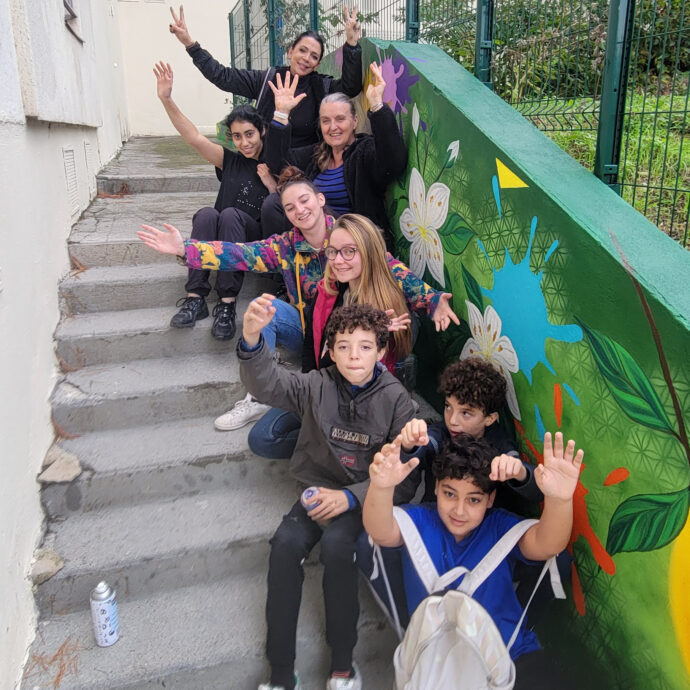 Florence Fabris entourée des adolescents et des participants devant la fresque colorée réalisée pour les jardins partagés de Carros.