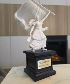 Sculpture de la statue de Ségurane par Florence Fabris : figure féminine blanche tenant un drapeau sur un socle noir avec plaque gravée SÉGURANE, exposée dans un intérieur chic avec vue sur Nice.